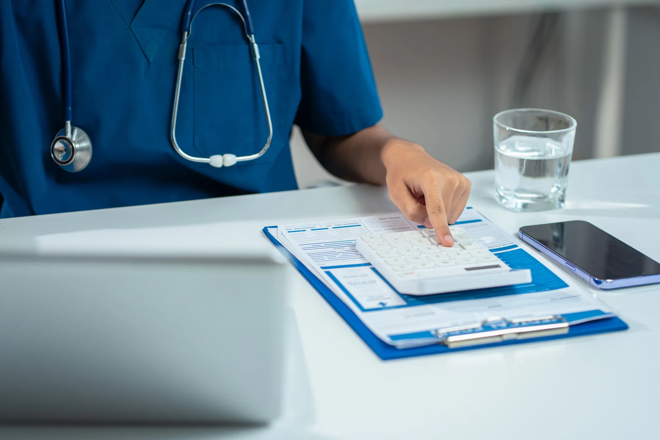 Healthcare professional using calculator at desk.