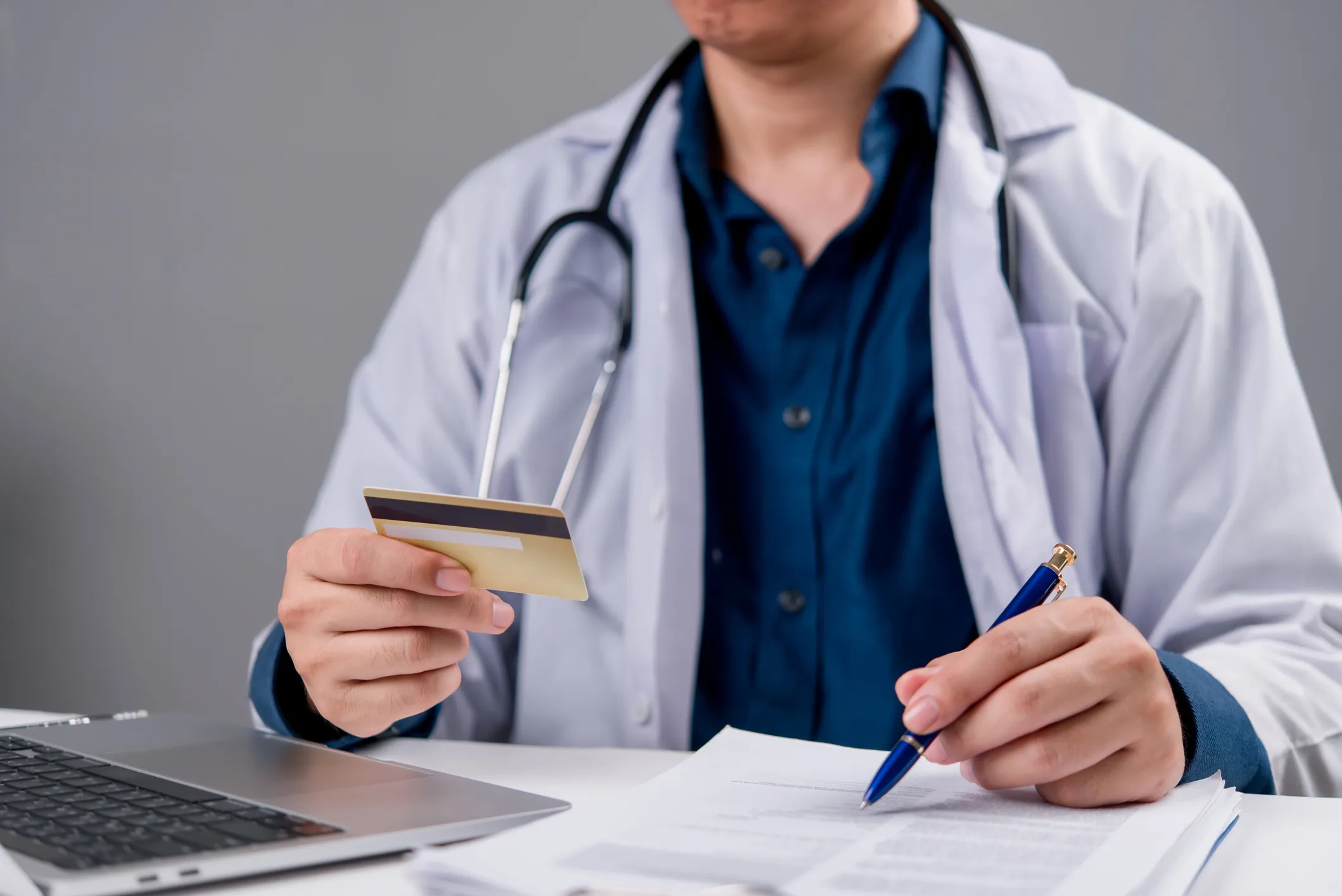 Doctor with stethoscope holding credit card.
